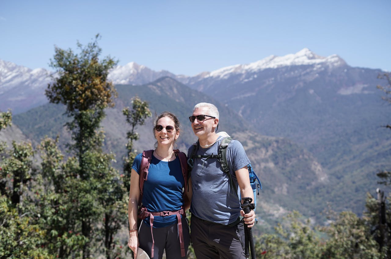 A smiling couple hikes in the scenic mountains of Uttarakhand, India.